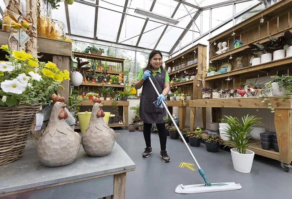 Schoonmaker aan het werk in een tuincentrum.