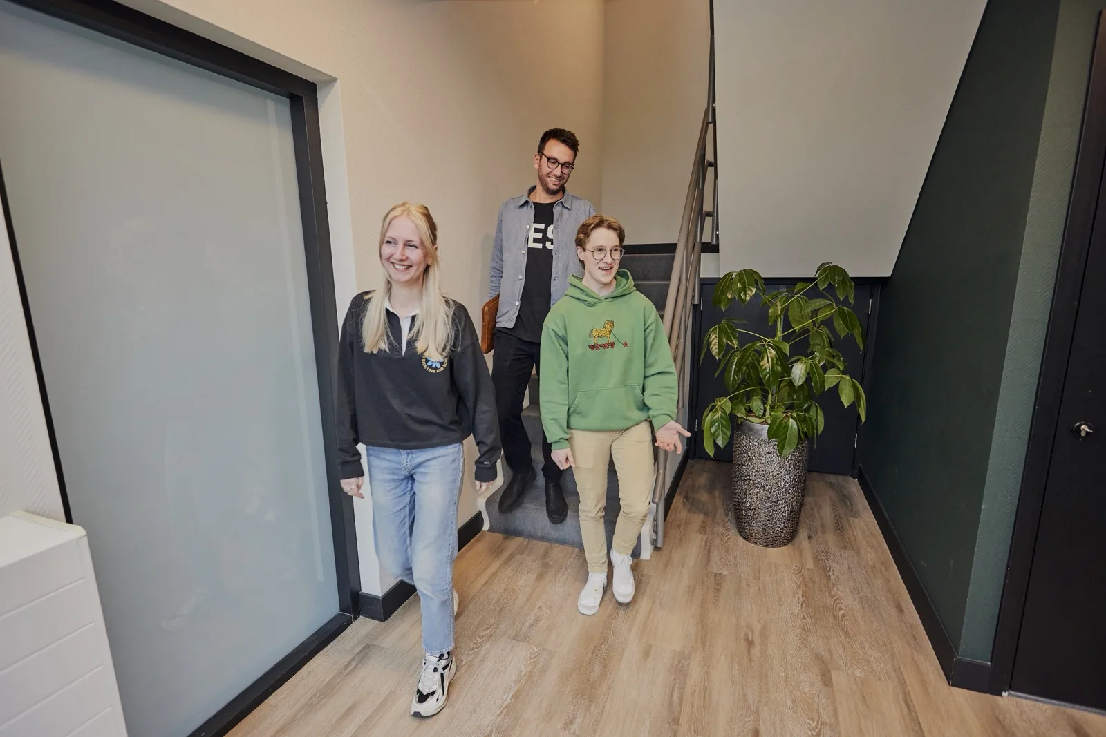 Drie collega's van Active Collective lopen samen door het kantoor