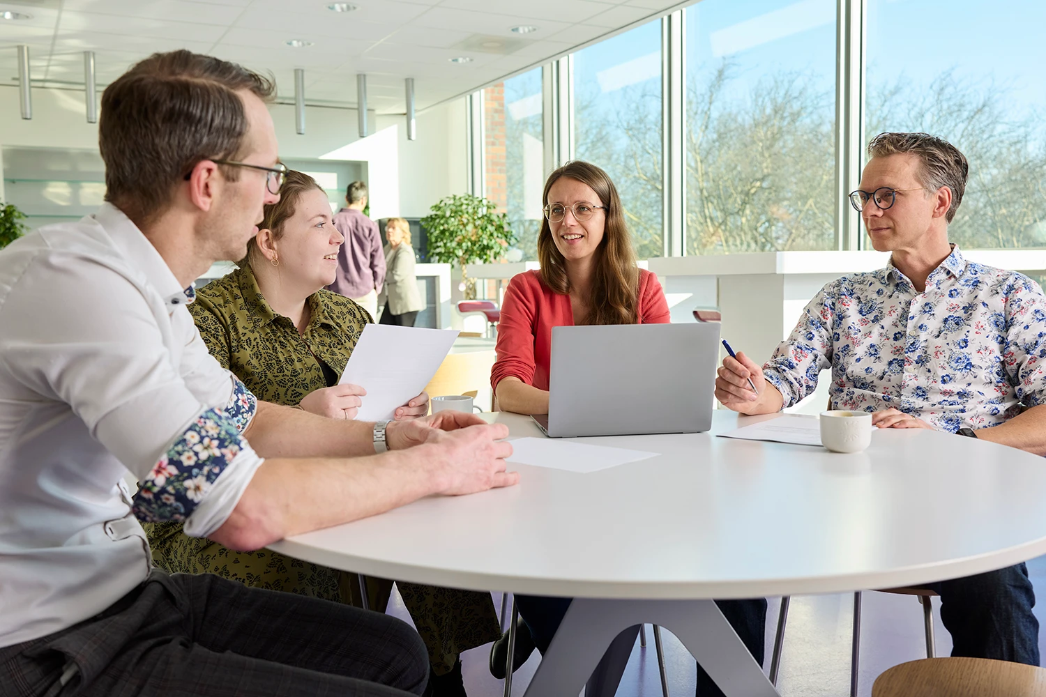 Vier PurSang-collega’s in gesprek rond een tafel.