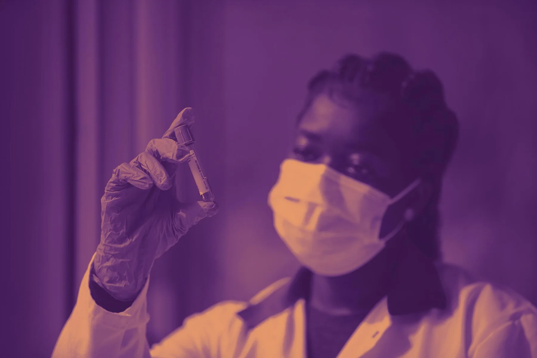 Laboratoriummedewerker houdt een samplebuis omhoog voor controle.